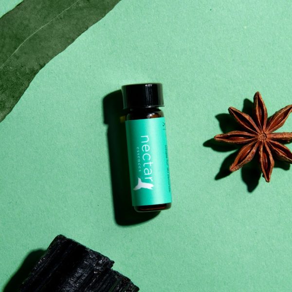 Amber 'nectar essences' bottle with a teal label, next to a star anise and a piece of black tourmaline on a green background.
