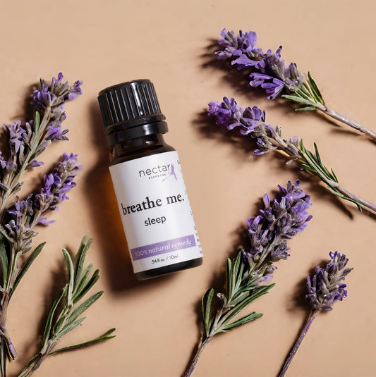 Flat lay of herbal branches with a ‘Breathe Me’ essential oil bottle, highlighting natural ingredients and wellness benefits.
