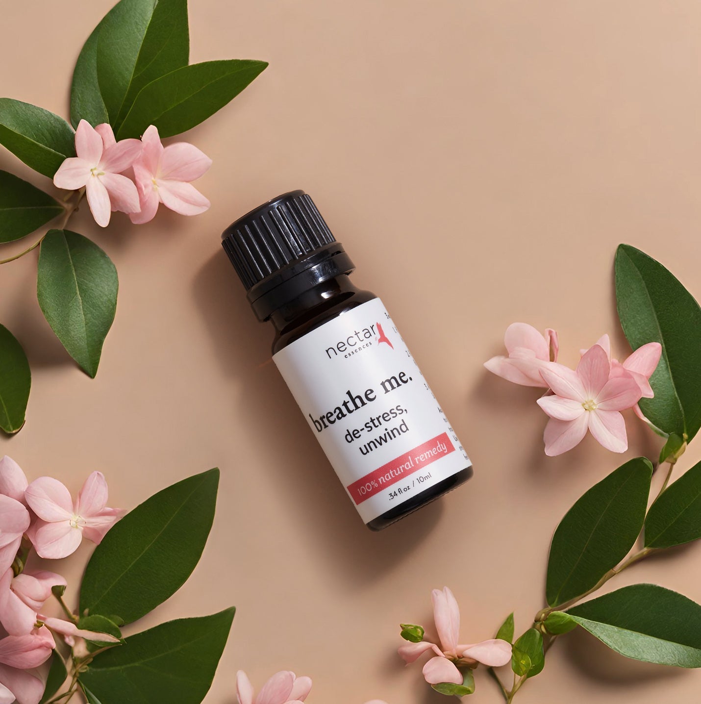 Flat lay of herbal leaves with gold roses, a ‘Breathe Me’ essential oil de stress bottle, highlighting natural ingredients and wellness benefits.