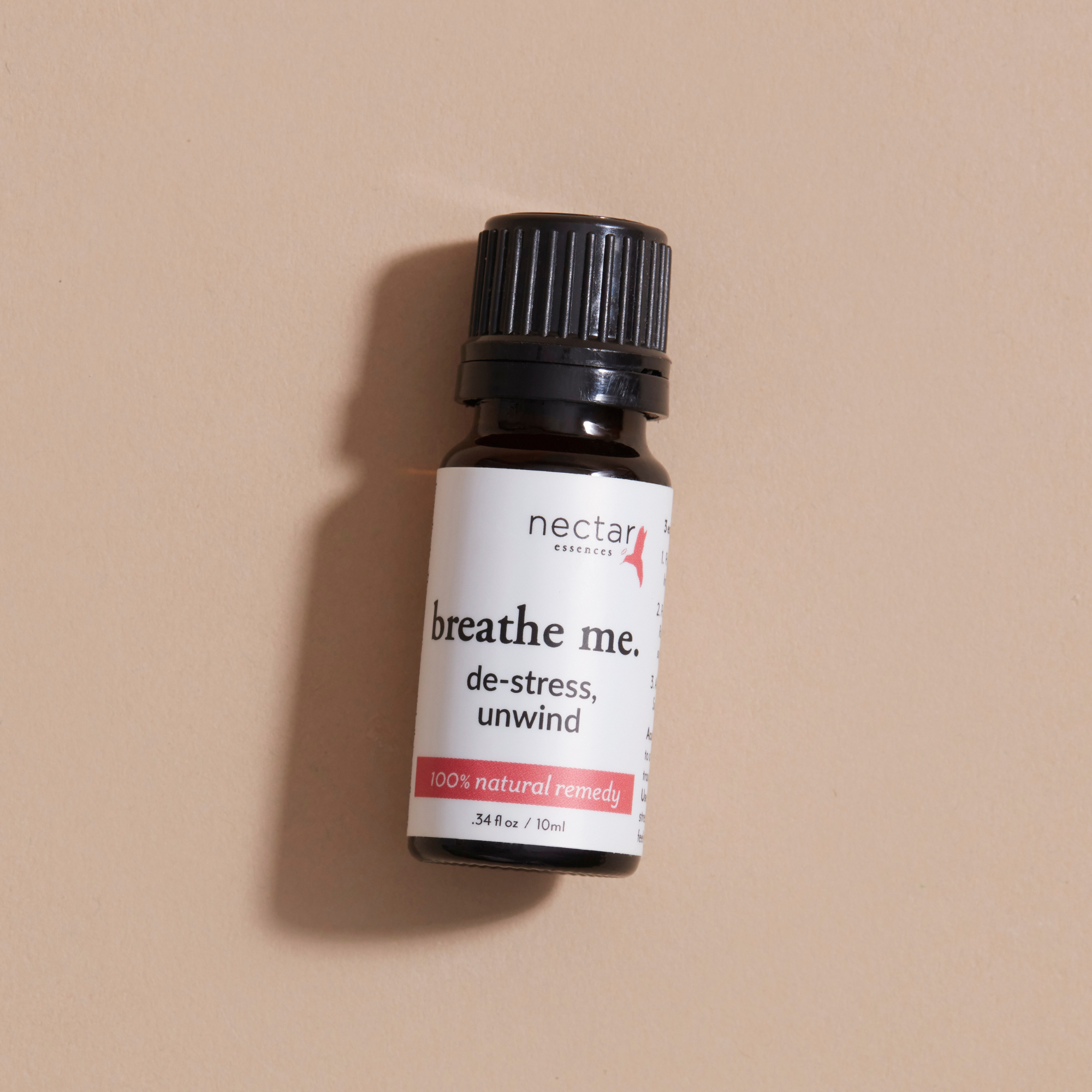 Small bottle laying labeled 'breathe me' with a beige background