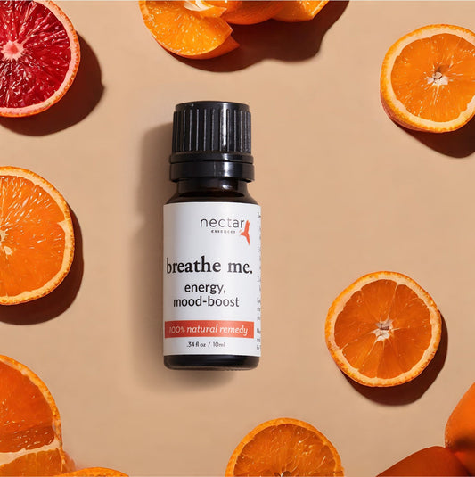 Flat lay of orange or lemon slices with a ‘Breathe Me’ essential oil energy mood boost bottle, highlighting natural ingredients and wellness benefits.