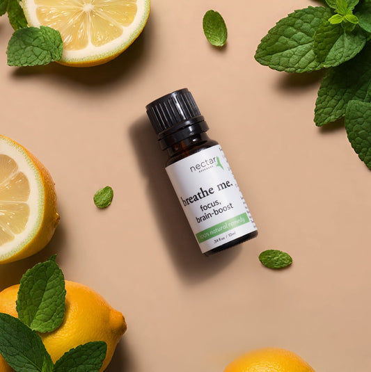 A flat lay of leaves of mint, half and full pieces of lemons essential oil bottles of breathe me focus brain boost and supplement.