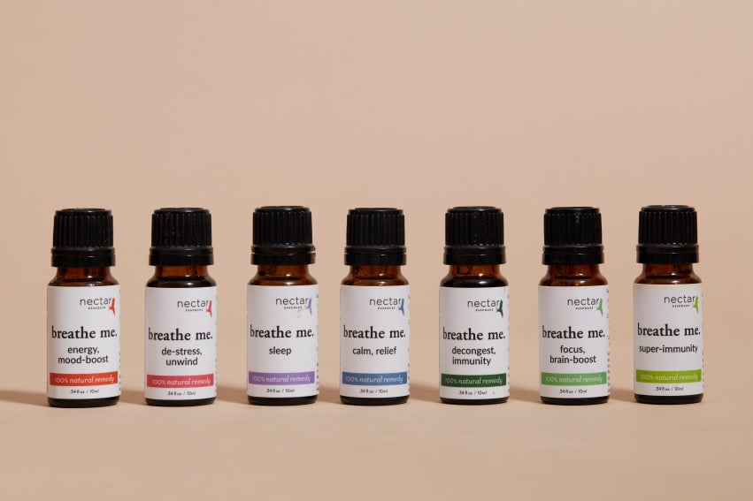 A set of seven essential oil bottles arranged in a row with their respective labels facing forward on a beige simple background.