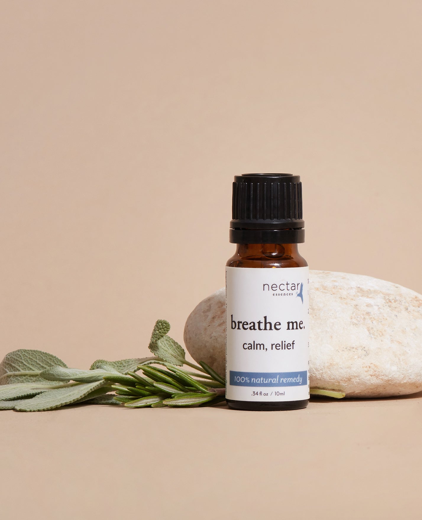 Bottle of 'breathe me' product calm relief essential oil with a rock and plant on a beige background