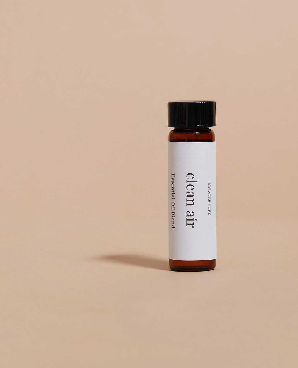 Vertical close-up of the small essential oil bottle against a vibrant blue background. The label is clearly visible, showing the white text 'clean Air' oriented vertically.