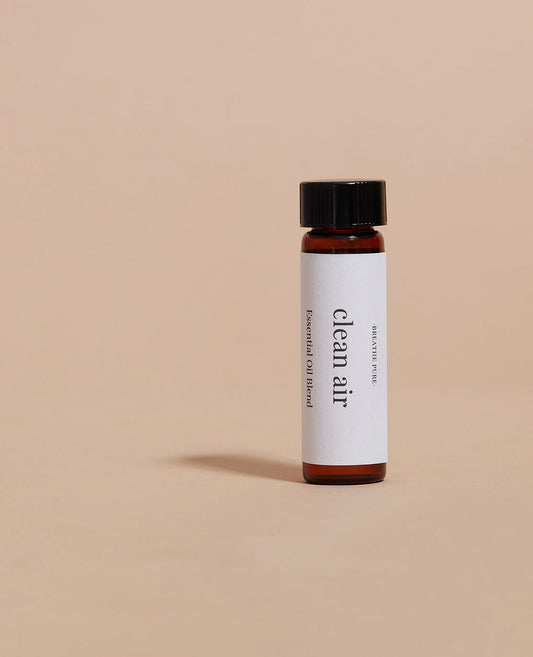 Vertical close-up of the small essential oil bottle against a vibrant blue background. The label is clearly visible, showing the white text 'clean Air' oriented vertically.