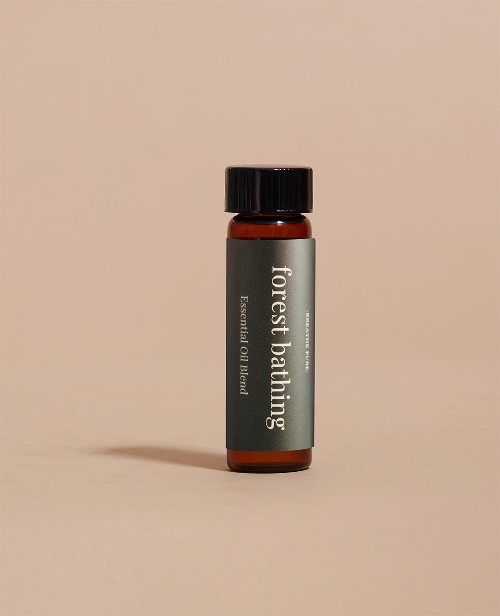 Forest Bathing Essential Oil Blend glass bottle with dark green label and black cap on a simple, minimalist beige background.