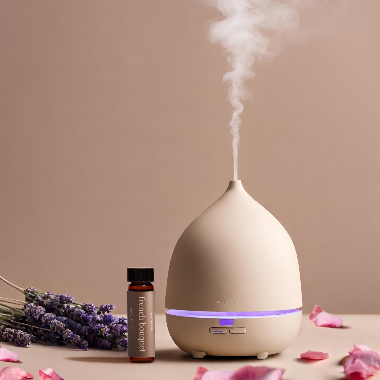 French Bouquet essential oil blend bottle next to a beige diffuser emitting steam, styled with fresh lavender and pink rose petals.