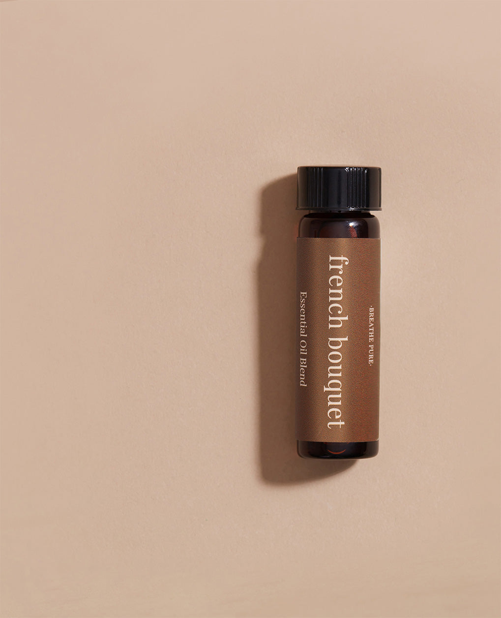 Close-up of French Bouquet Essential Oil Blend glass bottle with a soft brown label on a simple beige background.