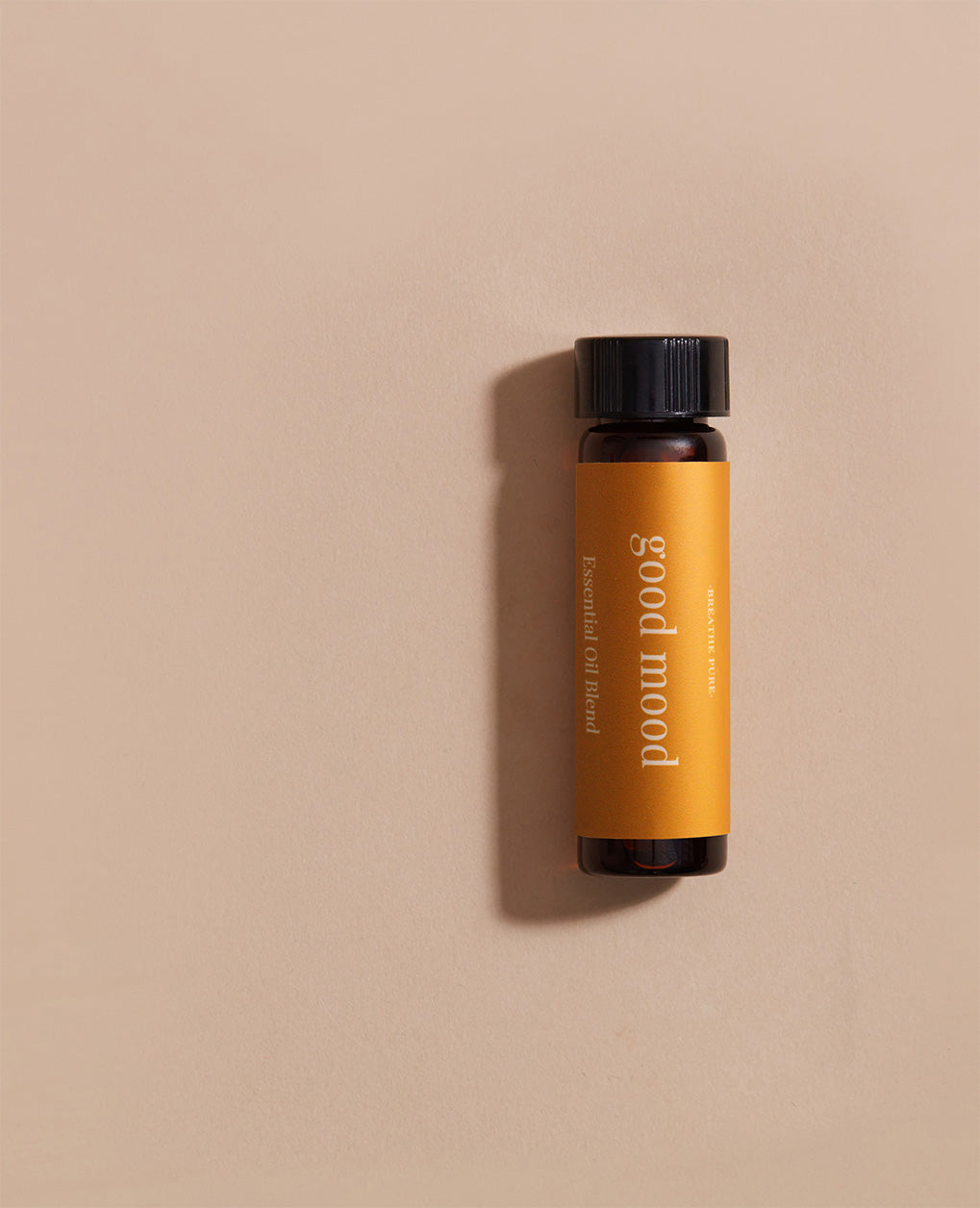 Vertical close-up of the small essential oil bottle laying against a light beige background. The label is clearly visible, showing the white text 'good mood' oriented vertically.