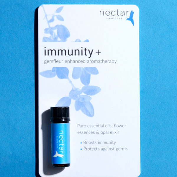 Product display card for the 'nectar essences' Immunity+ blend. The white card features a light blue graphic of oregano leaves and text reading 'immunity + gemfleur enhanced aromatherapy.' A small bottle of the blue-labeled essential oil is resting at the bottom. The text lists benefits: 'Pure essential oils, flower essences & opal elixir,' 'Boosts immunity,' and 'Protects against germs.