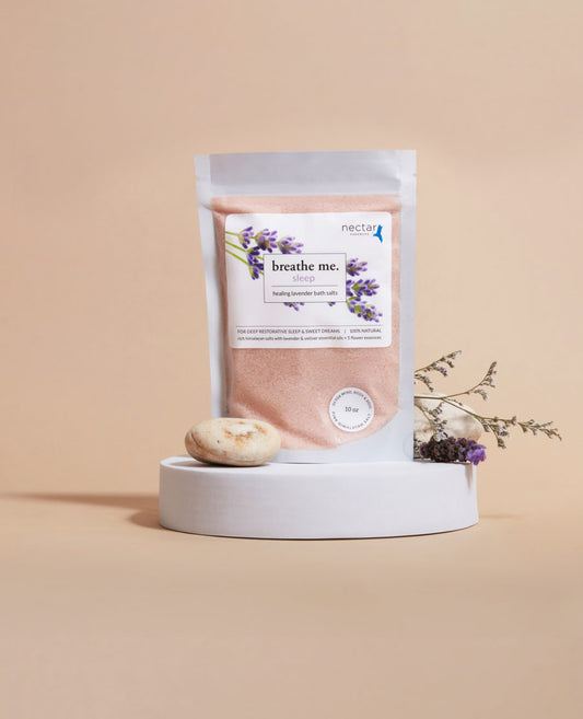 A pouch of sleep healing bath salt with lavender oil and pink himalayan salt, presented on a white platform with decorative dry flowers beside it.