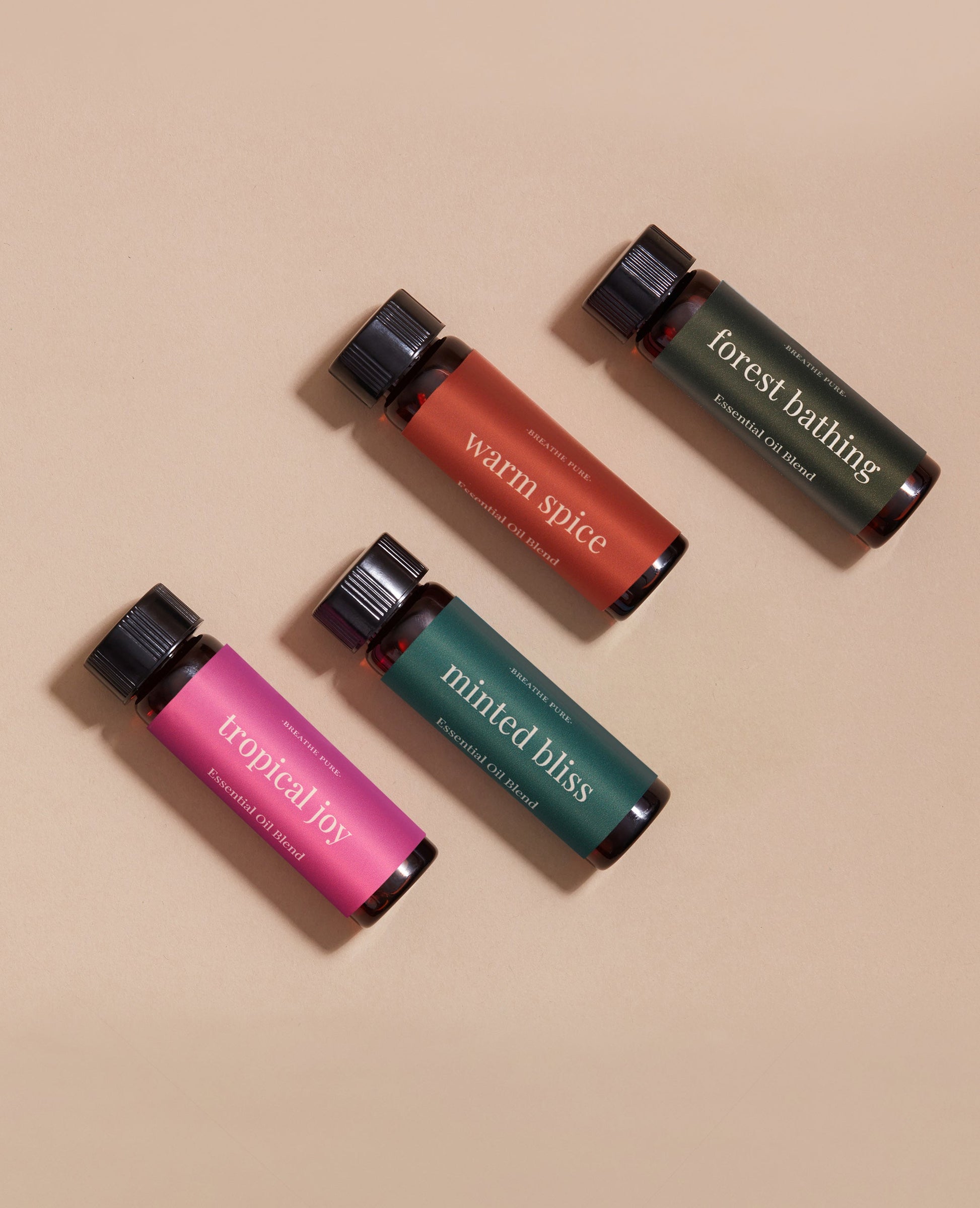 Group shot of four essential oil blends: Tropical Joy, Warm Spice, Minted Bliss, and Forest Bathing bottles.