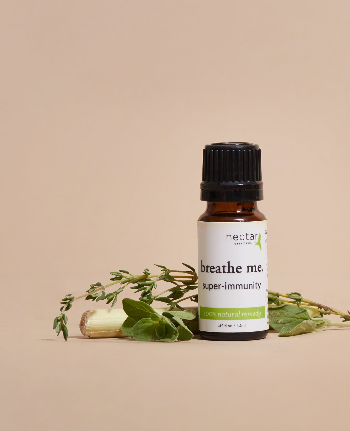 Bottle of 'breathe me. super-immunity' essential oil with herbs on a beige background