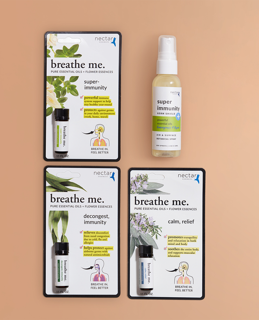 A set of aromatherapy products including essential oil bottles and packaging with 'breathe me' written on them, against a beige background.