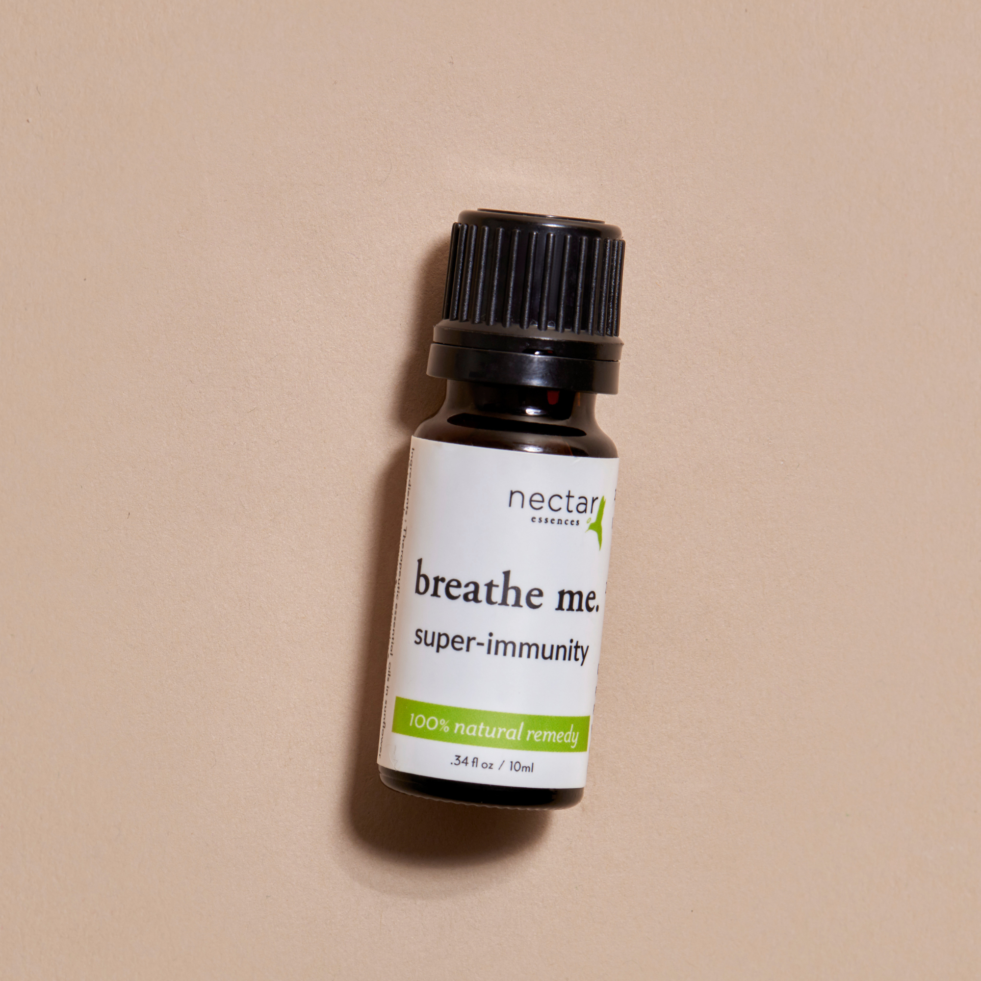 Small bottle labeled 'breathe me. super-immunity' by 'nectar' laying on a beige background