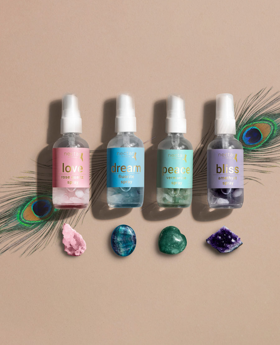 This image features a collection of vibrational spray bottles, each distinctively labeled and arranged in a row. The labels on the bottles suggest different names such as "Love," "Peace," "Joy," and "Bliss," indicating a range of emotional or spiritual states aimed at fostering a positive atmosphere.